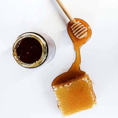 An overhead image of honey, some honeycomb, and a jar of honey.